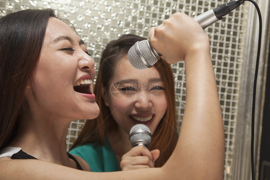 两个年轻女性朋友在卡拉OK唱歌 唱到一个麦克风图片
