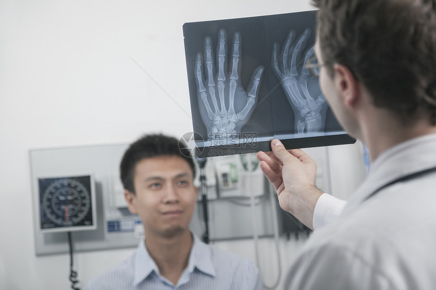 医生举起手来 看X光检查病人的手骨 背景病人的手提骨图片