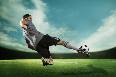 卫冕足球运动员在半空中踢足球 在有天空的体育场内背景