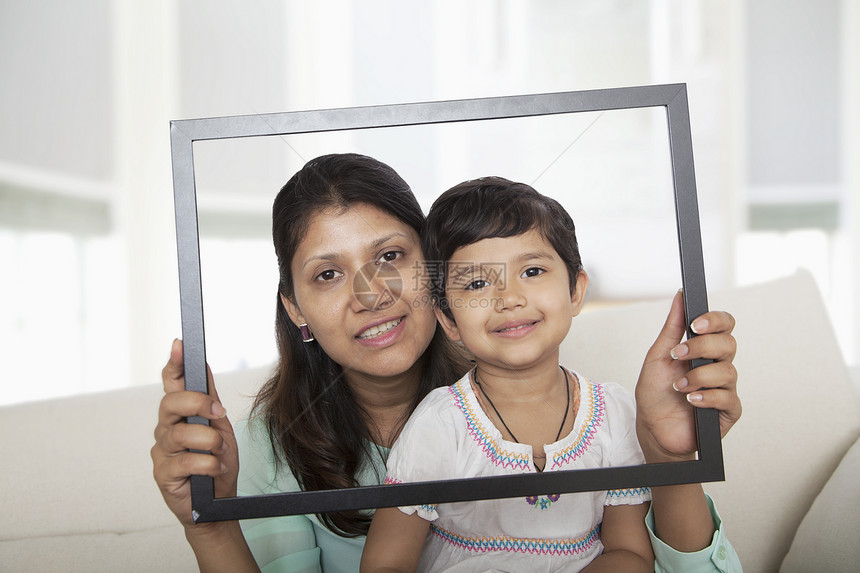 母亲和女儿举着一幅图片框 透过它看一看图片
