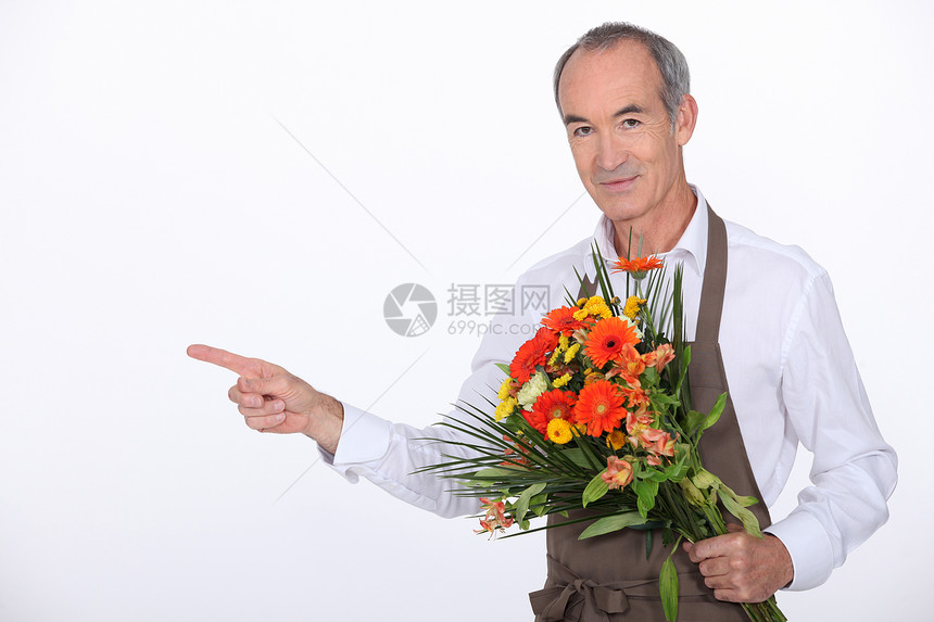 65岁的男性花店男花商 拿着花束 用手指指着什么东西图片