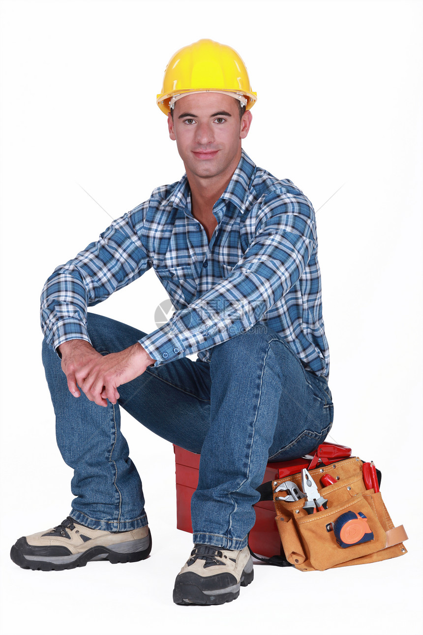 一个建筑工人坐在他的工具箱上图片