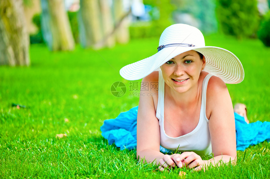 年轻美丽的笑笑女孩 在草坪上放松 戴着白帽子图片