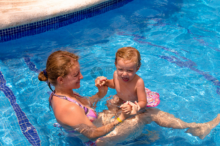 游泳池中的母亲和女儿娱乐父母女士阳光享受水池假期女孩孩子消遣图片