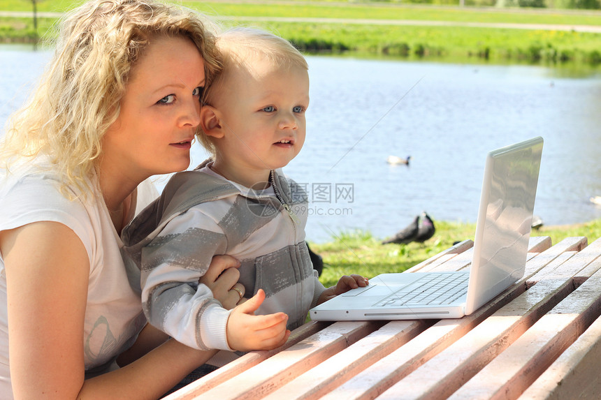 使用手提笔记本电脑的母婴花园教育孩子公园母亲草地金发童年幸福互联网图片