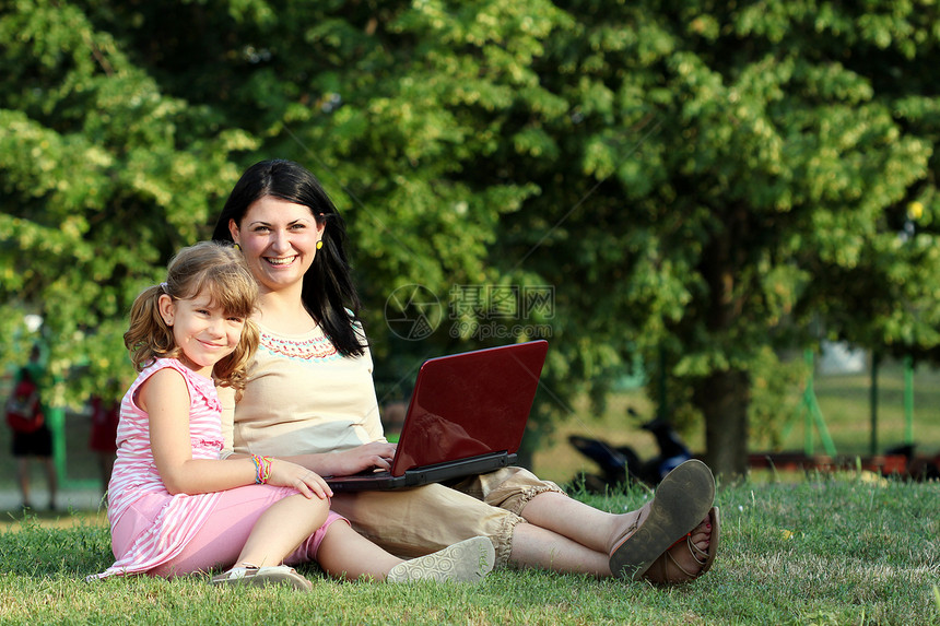 快乐的小女孩和女人 在公园有笔记本电脑图片
