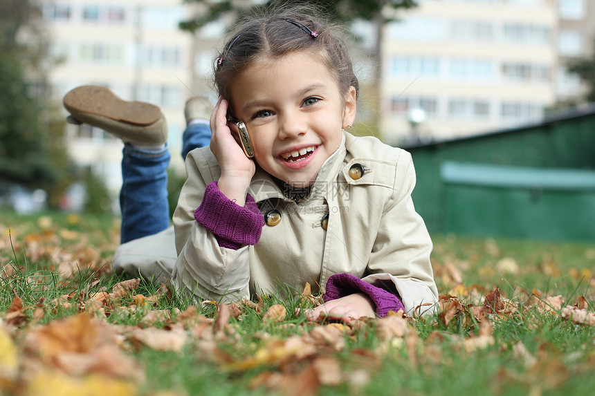 小女孩在手机上说话笑声头发孩子谎言季节公园微笑幸福黑发快乐图片