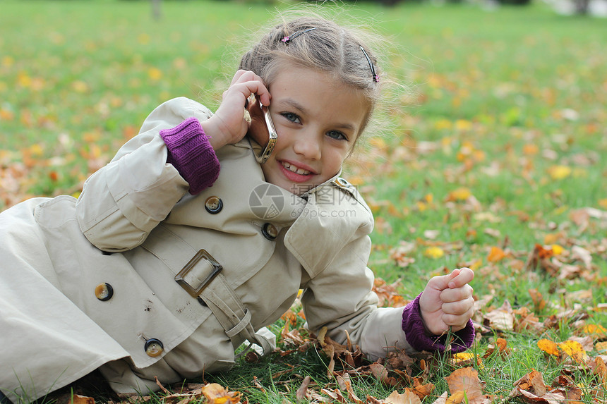小女孩在手机上说话讲话女性季节谎言大衣享受快乐闲暇头发微笑图片