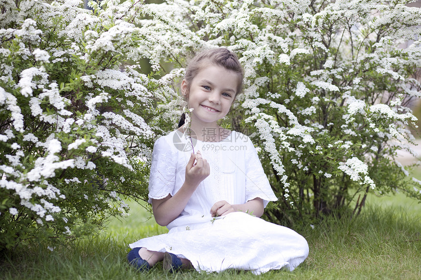 春花中美丽的小女孩的肖像童年孩子女学生女性植物衬套裙子冒充头发灌木图片
