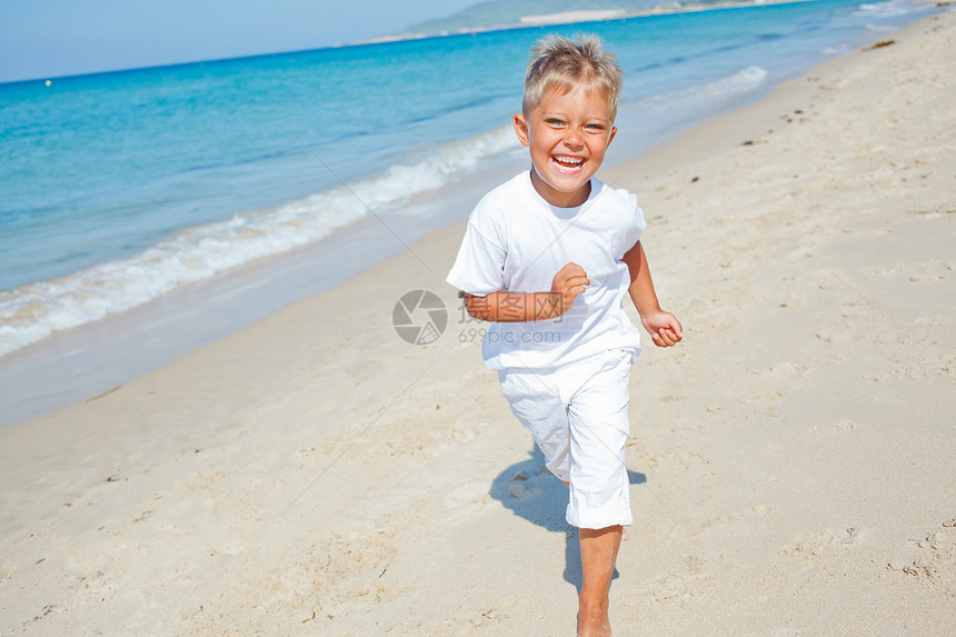 海滩上可爱的男孩海洋太阳幸福地平线活动男生跑步海岸眼镜假期图片