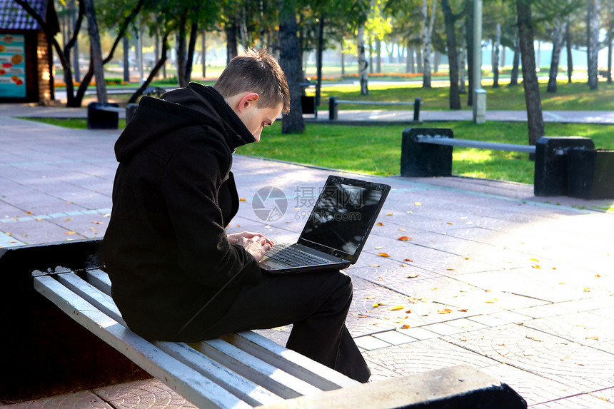 在公园的笔记本电脑工作的人成人外套长椅工具叶子操作互联网面漆小路头发图片