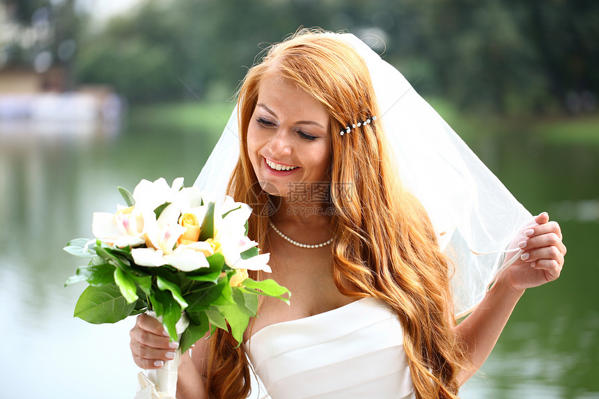 穿着婚纱的美丽红发新娘幸福女性婚姻面纱裙子公园派对快乐花朵女孩图片