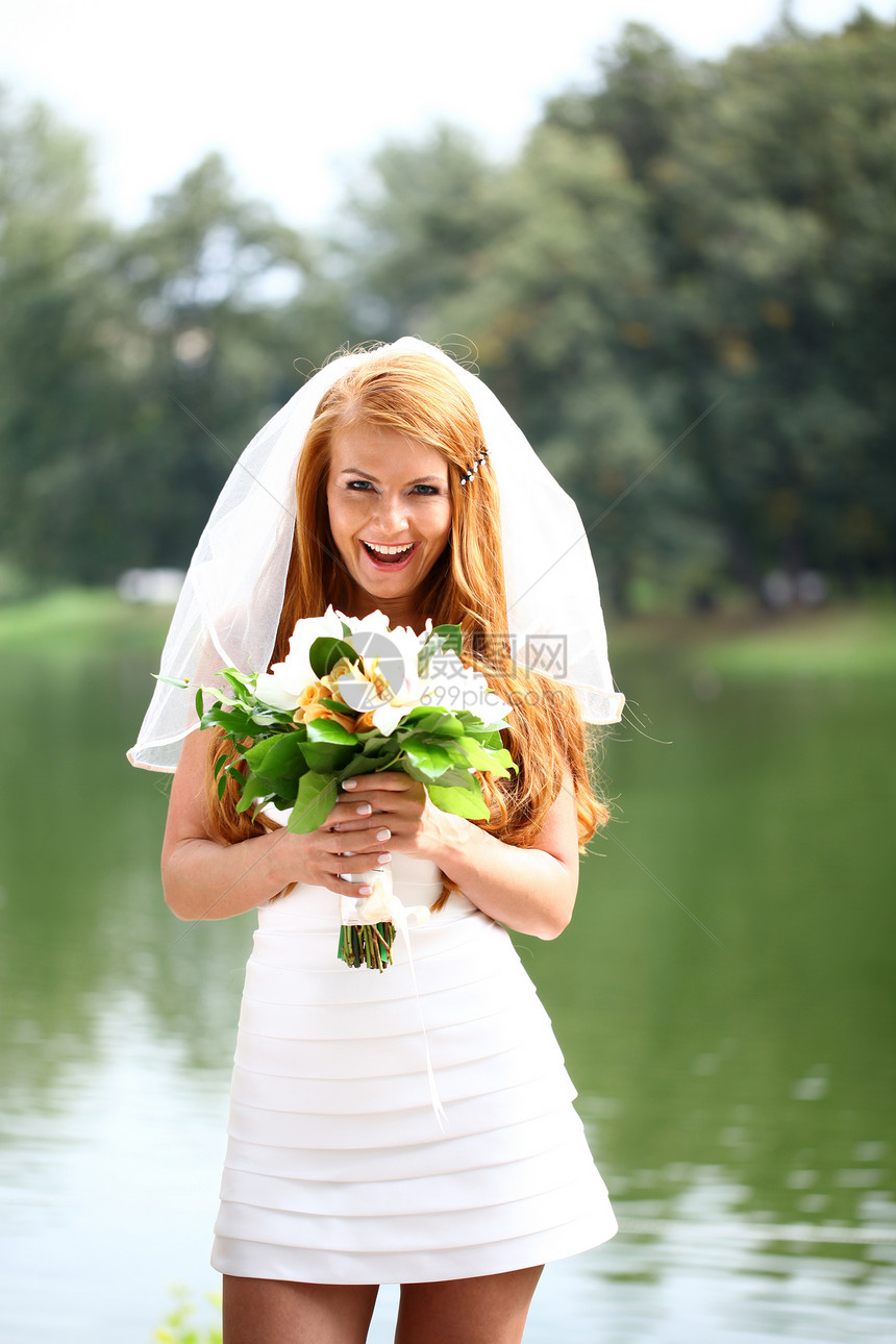 穿着婚纱的美丽红发新娘公园花朵女性婚姻礼服裙子派对青年花束快乐图片