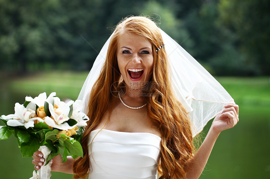 穿着婚纱的美丽红发新娘礼服花束裙子婚礼女性微笑女孩婚姻快乐公园图片
