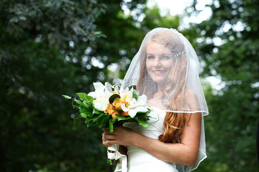 穿着婚纱的美丽红发新娘女孩婚姻花束婚礼快乐女性面纱裙子礼服公园图片