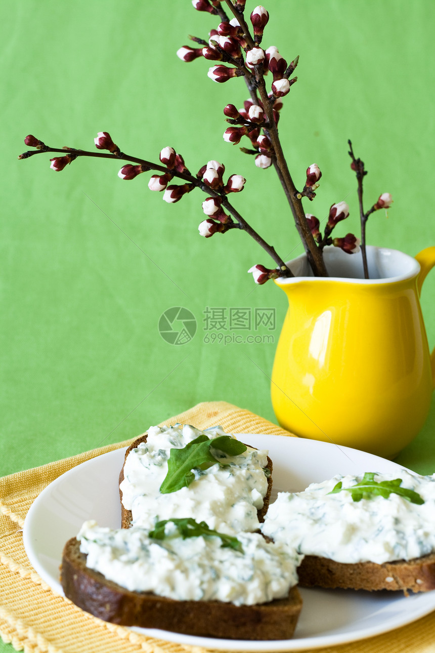 黑麦面包和花束上的奶酪小吃黑色绿色青菜餐巾黄色盘子面包投手花朵花瓶图片