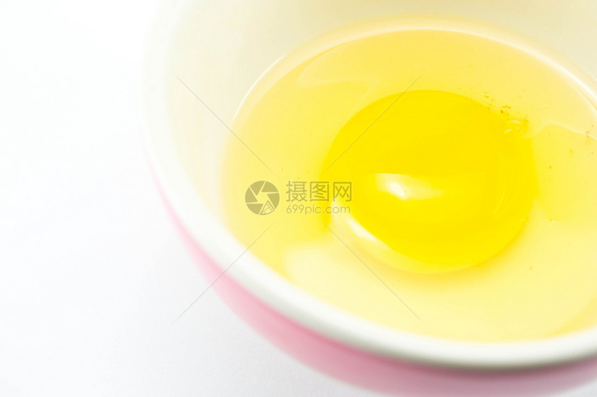 白色背景的杯子里生鸡蛋黑色蛋黄圆圈反射黄色早餐平底锅烹饪食物饮食图片