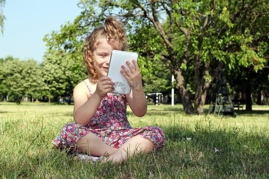 快乐的小女孩与平板电脑 Pc在公园图片
