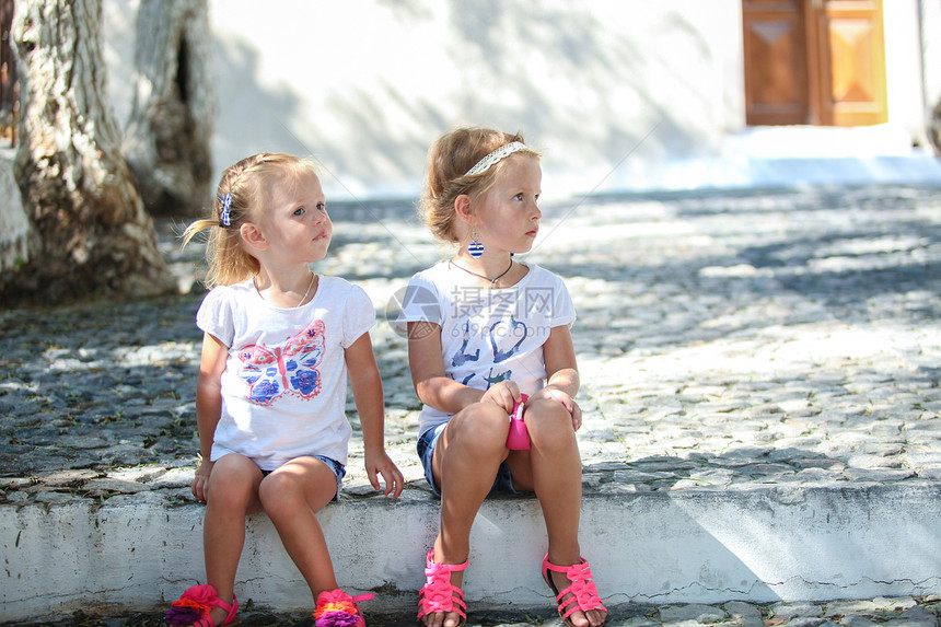 坐在桑托里尼Emporio老希腊村街头的年轻迷人女孩文化传统房子假期衣服商场建筑胡同蓝色女儿图片