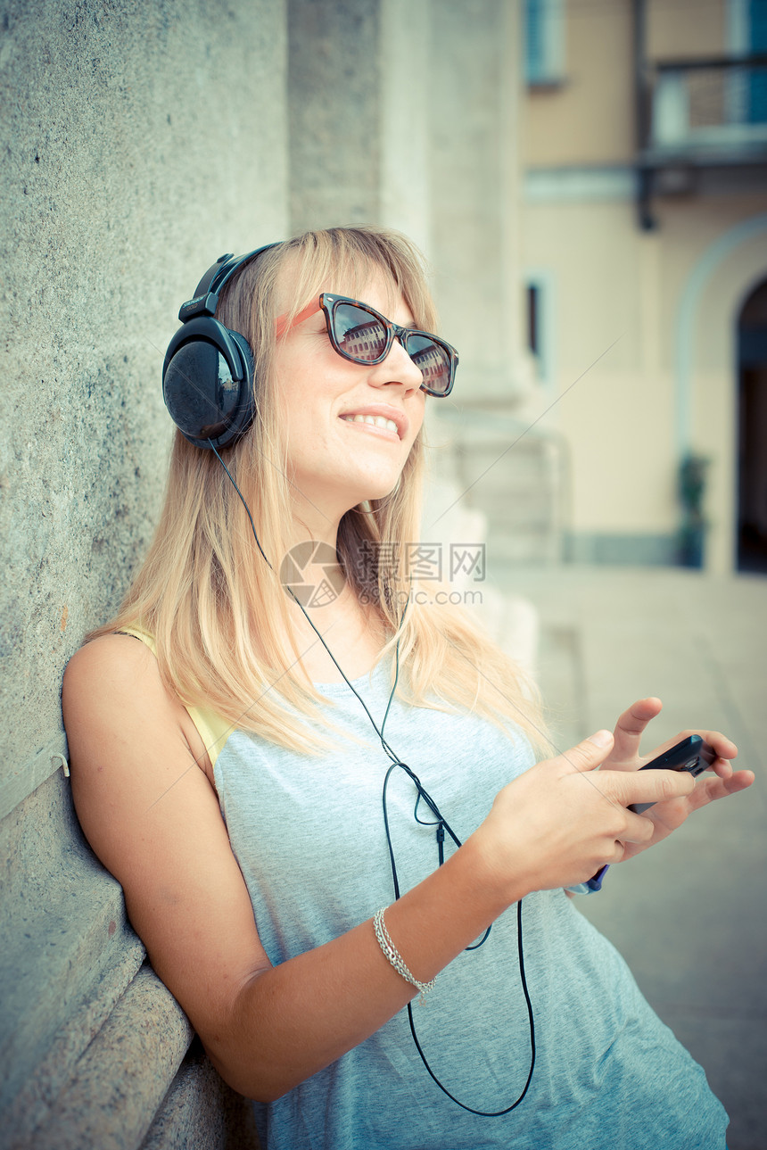 听音乐的美丽金发美女女士音乐潮人耳机太阳镜玩家街道幸福金发女郎城市图片