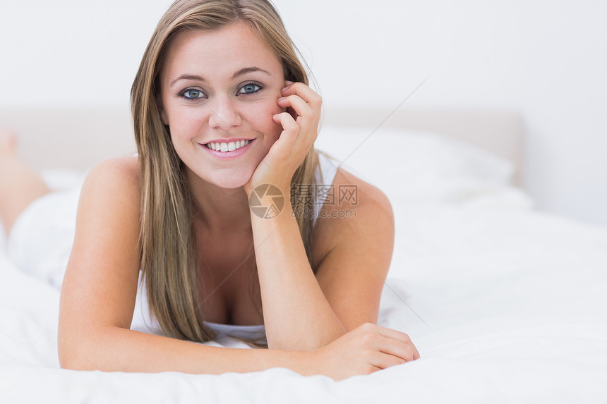 快乐的女人躺在床上女士金发浅色头发白色微笑女性卧室金发女郎坐垫图片