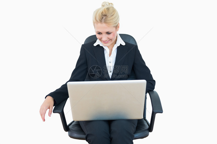开心的女商务人士在椅子上使用笔记本电脑图片