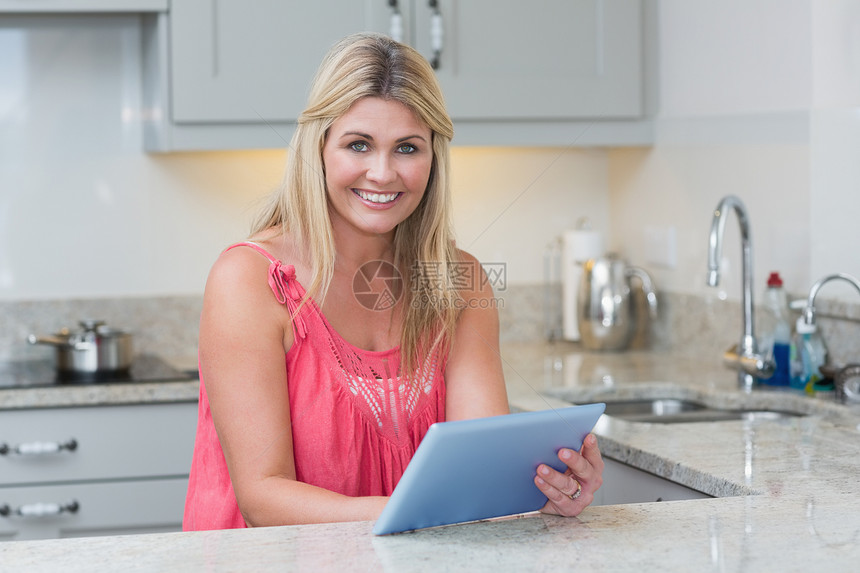 在厨房使用数字平板电脑的临时妇女肖像图片