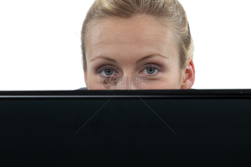躲藏在膝上型计算机后面的妇女图片