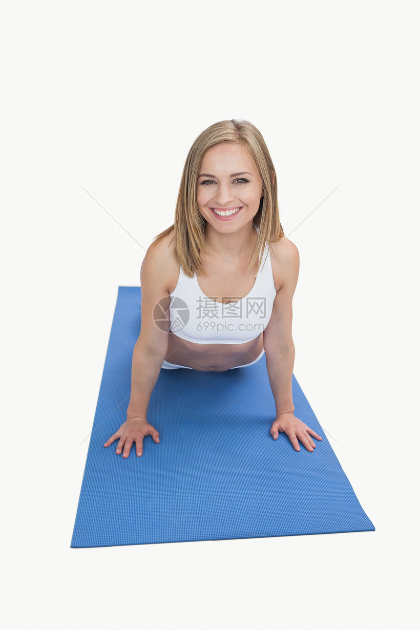 快乐女人在运动垫上做俯卧撑的肖像图片