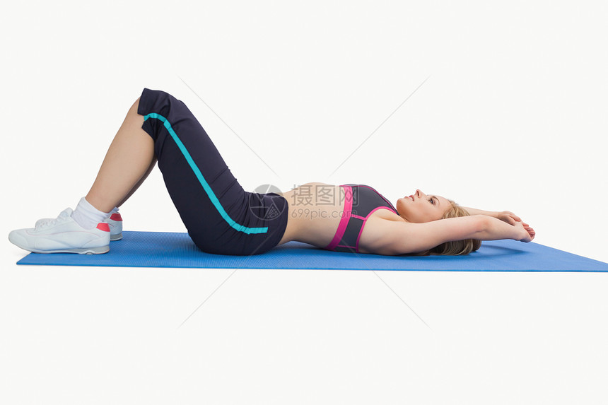 在瑜伽垫子上穿运动服的妇女的侧视角图片