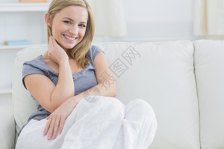 坐在沙发上的放松女人的肖像家庭生活房子头发浅色金发闲暇长椅女性客厅女士背景图片