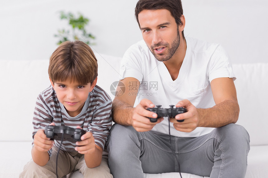 父亲和儿子玩电子游戏客厅混血男人棕色视频按钮男生男性微笑家庭图片