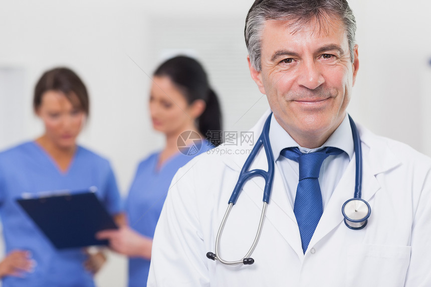 带着听诊器微笑的医生和他的团队在他身后图片