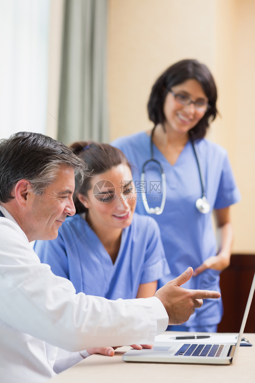 医生在笔记本电脑上给护士看东西实验服务女性技术桌子工作服讨论团队办公室卫生图片