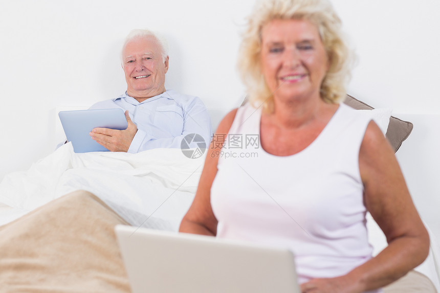 使用平板电脑和笔记本电脑对老夫妇微笑图片