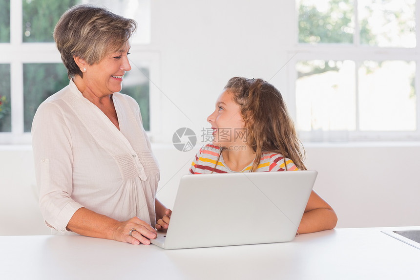 微笑的孩子和奶奶用笔记本电脑看望着图片
