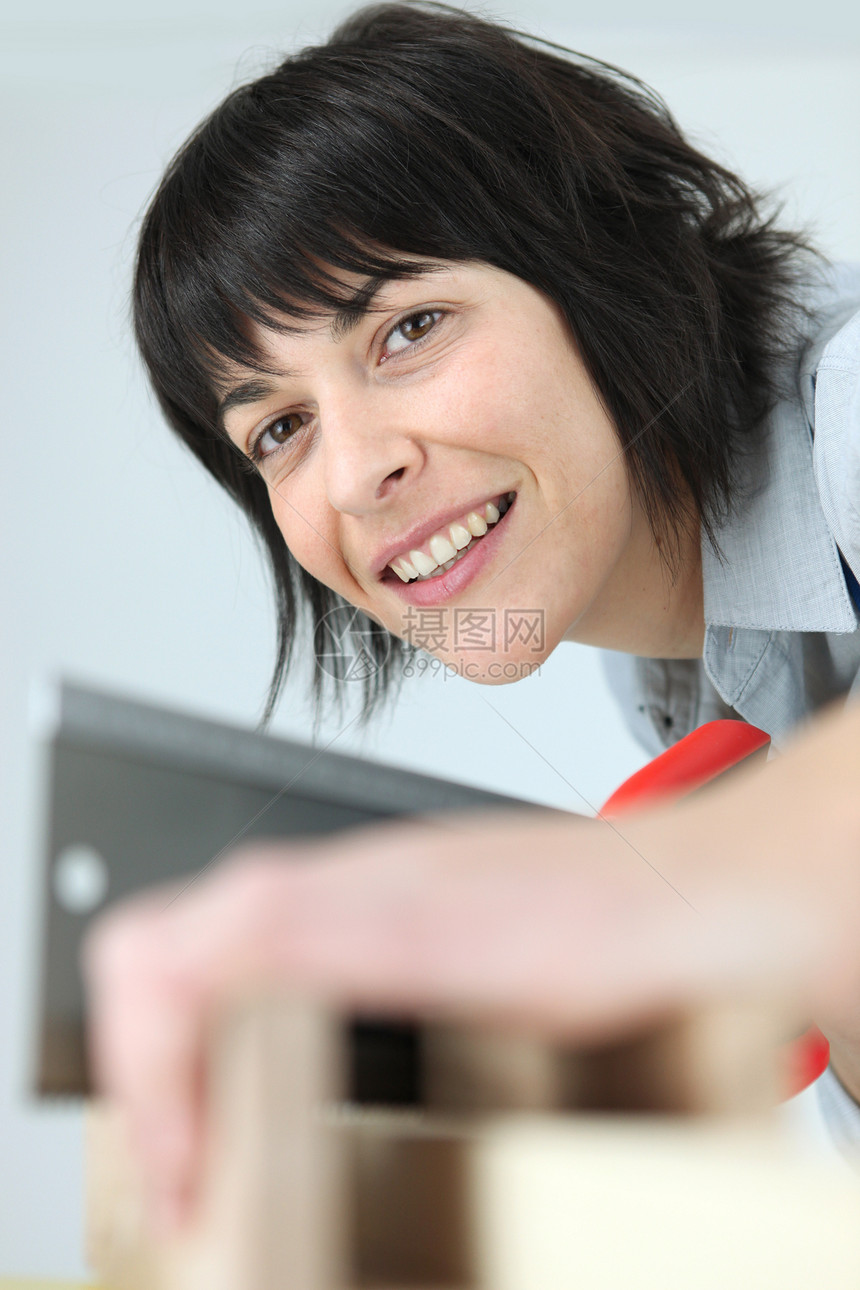 有锯子的女人木头手锯工具作坊女士工业橱柜运动木材专注图片