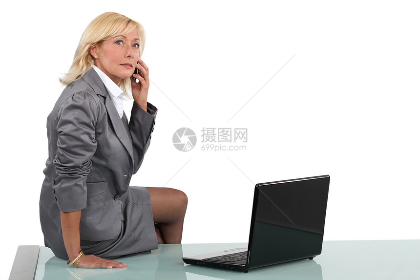 高级女商务人士坐在她的办公桌上图片