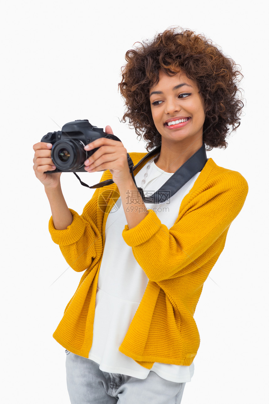 微笑的女孩拿着数码相机 看着它看图片