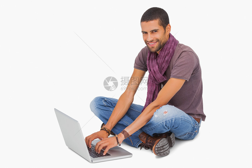 坐在地板上使用笔记本电脑的快乐男人图片