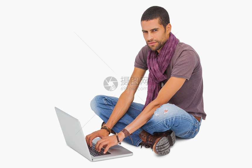 使用笔记本电脑坐在地板上的时尚男子牛仔布混血靴子男人男性潮人胡子围巾技术胡须图片