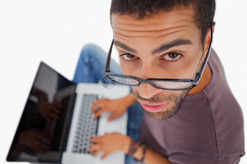 男人用笔记本电脑在地板上戴眼镜 抬头看图片