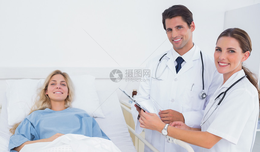 站在病人旁边的微笑的医生图片