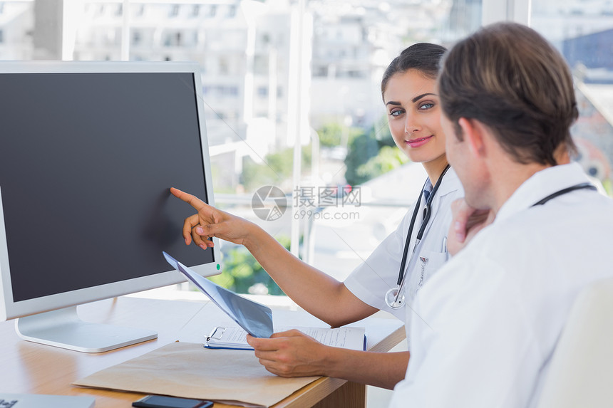将计算机屏幕显示给同事看的医生图片