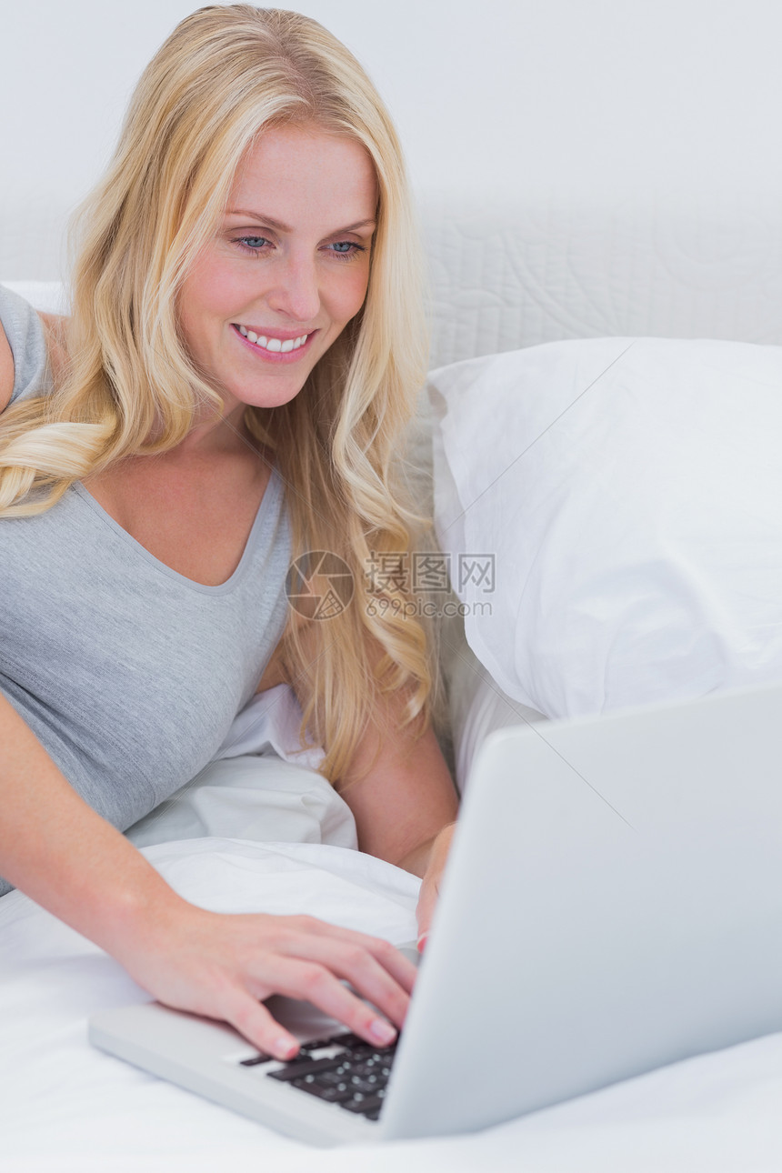 女人用笔记本电脑在床上打字图片