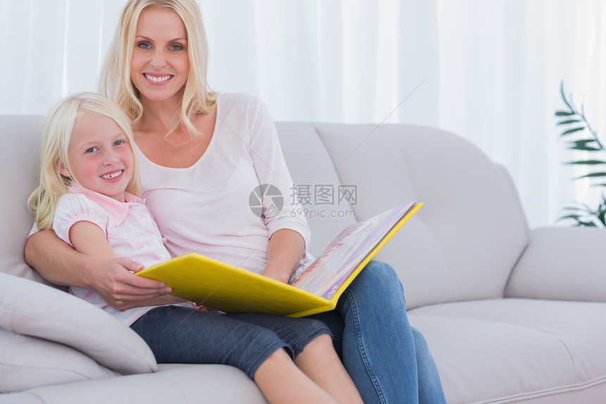 母亲和女儿坐在沙发上看书图片