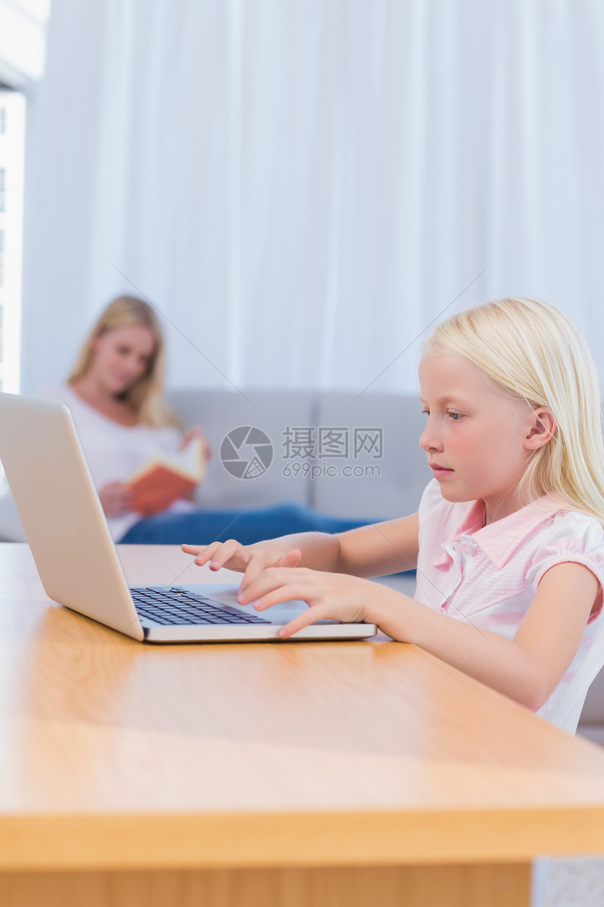 小女孩在客厅用笔记本电脑打字图片