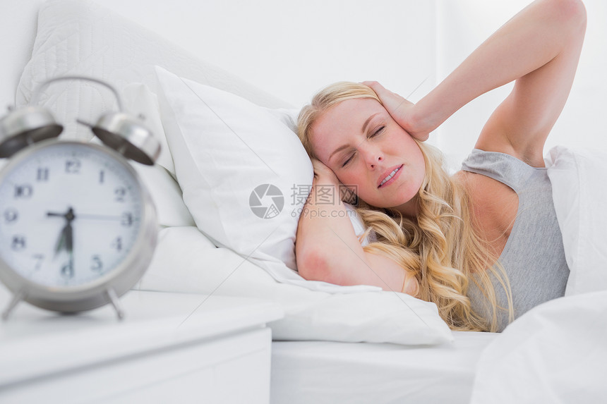 疲倦的金发女人 用双手遮耳朵图片