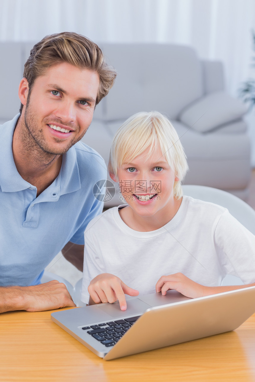 父亲和儿子用笔记本电脑男生休息室孩子房子客厅微笑沙发住所金发快乐图片