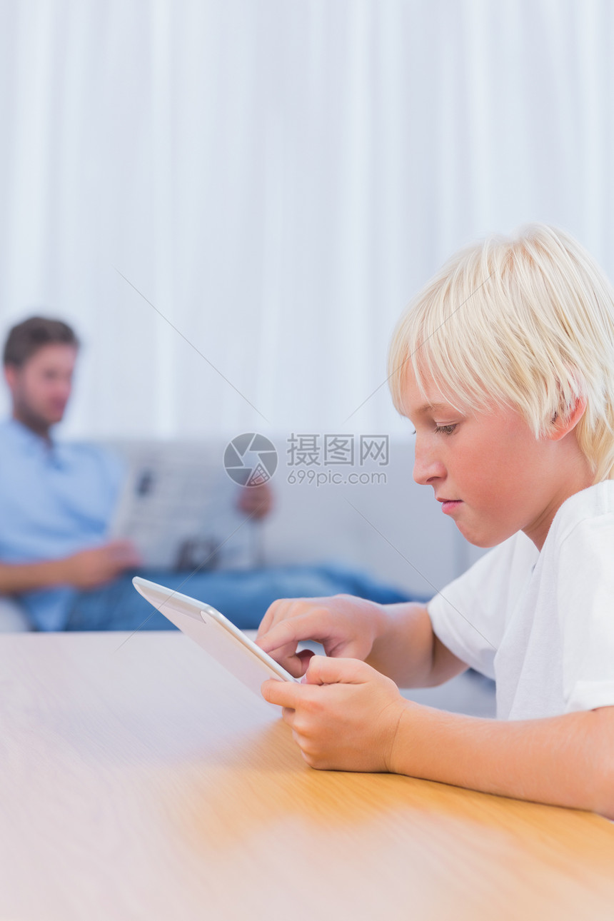 小男孩在客厅里使用数字平板电脑图片